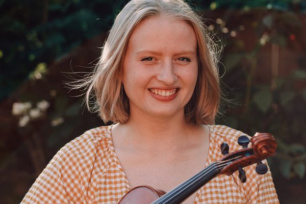 Woman smiling holding a violin - Benslow Music Course Tutor
