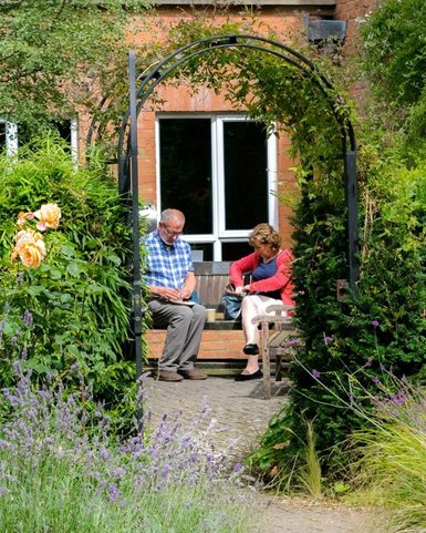 Couple relaxing in garden, sitting a bench