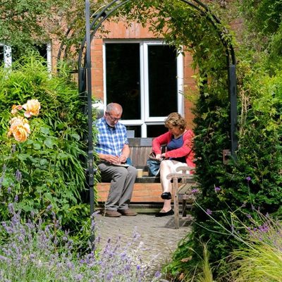 Couple relaxing in garden, sitting a bench