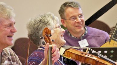 two men and a woman laughing while playing instruments