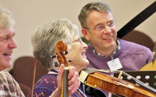 two men and a woman laughing while playing instruments