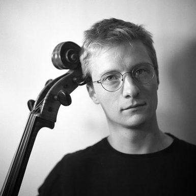 Black and white image of Ben Michaels with the neck of his cello showing